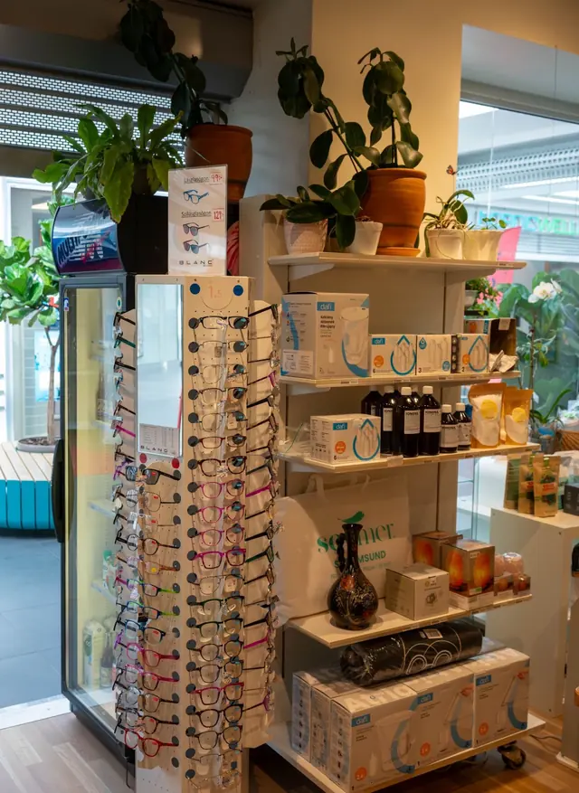 Läsglasögon på ett ställ intill vattenfilter och gröna växter i Hälsokraft Orminge